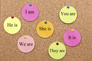 A picture of pronouns written on tags and pinned to a corkboard.